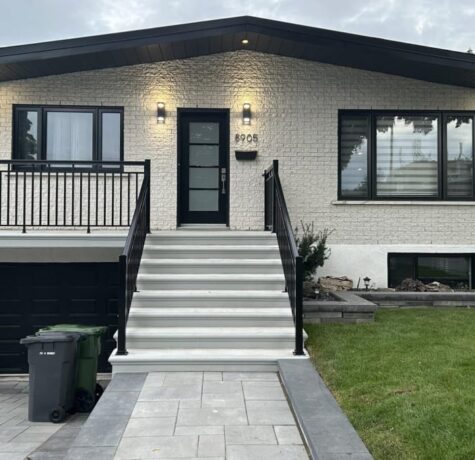 Maison rénovée avec brique peinte au spray, fenêtres noires et escalier moderne à Longueuil.