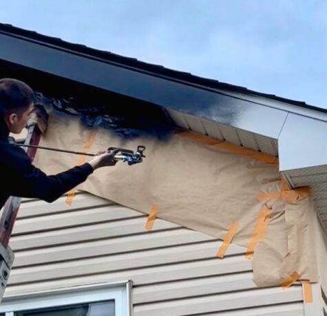 Application de peinture au spray sur des soffites extérieurs par un professionnel de Protech Peinture, avec ventilation soigneusement préservée.